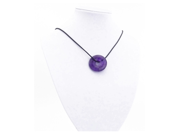 Pendentif donut améthyste porté sur un collier noir devant fond blanc