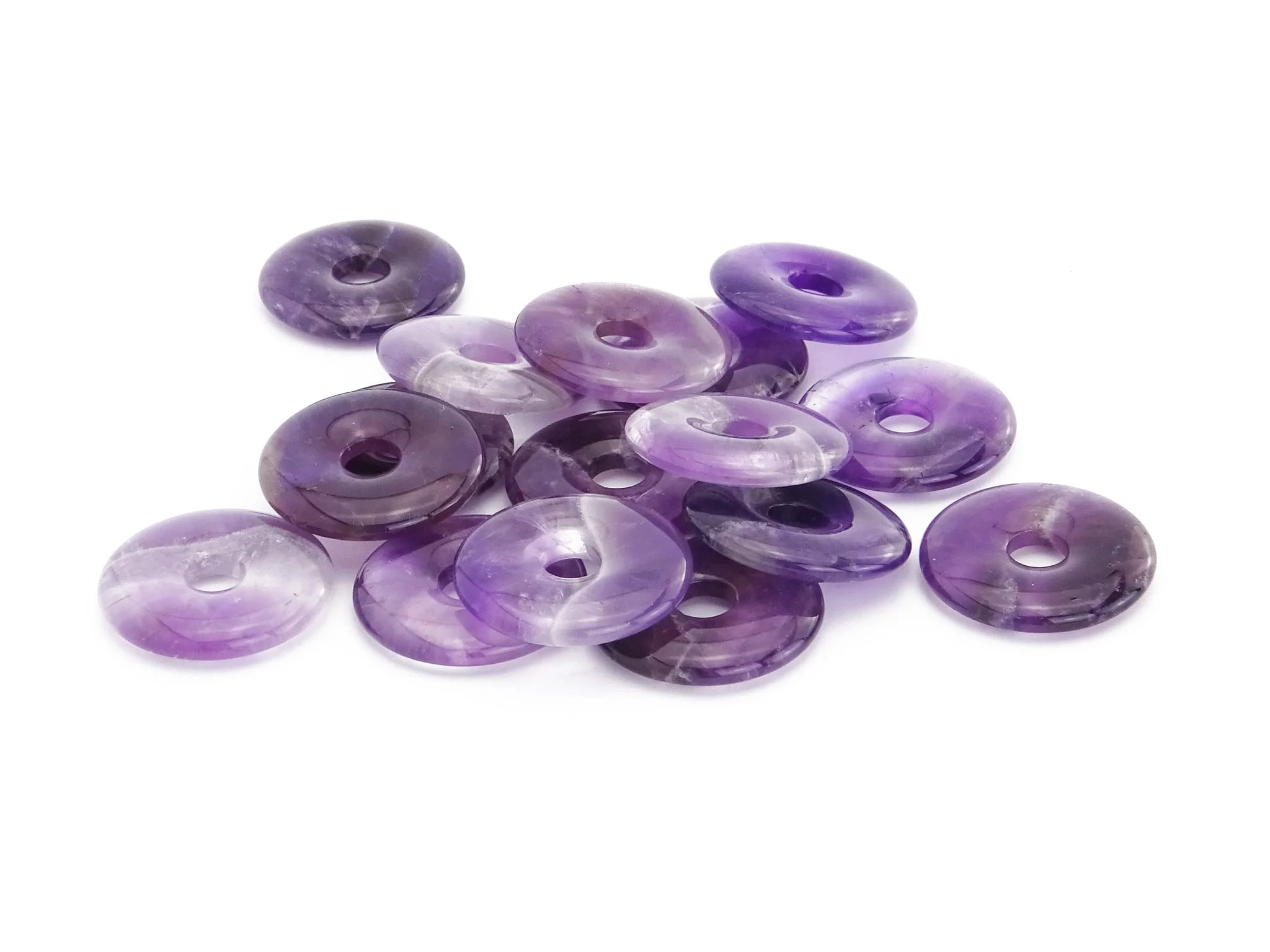 Pendentif donut améthyste comme groupe de pierres donut violettes polies sur fond blanc