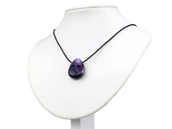 Pendentif en améthyste porté sur un buste de bijou blanc avec un collier noir