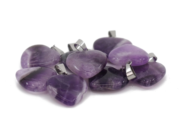 Amethyst heart gemstone pendant detail view of several violet pendants on a white background