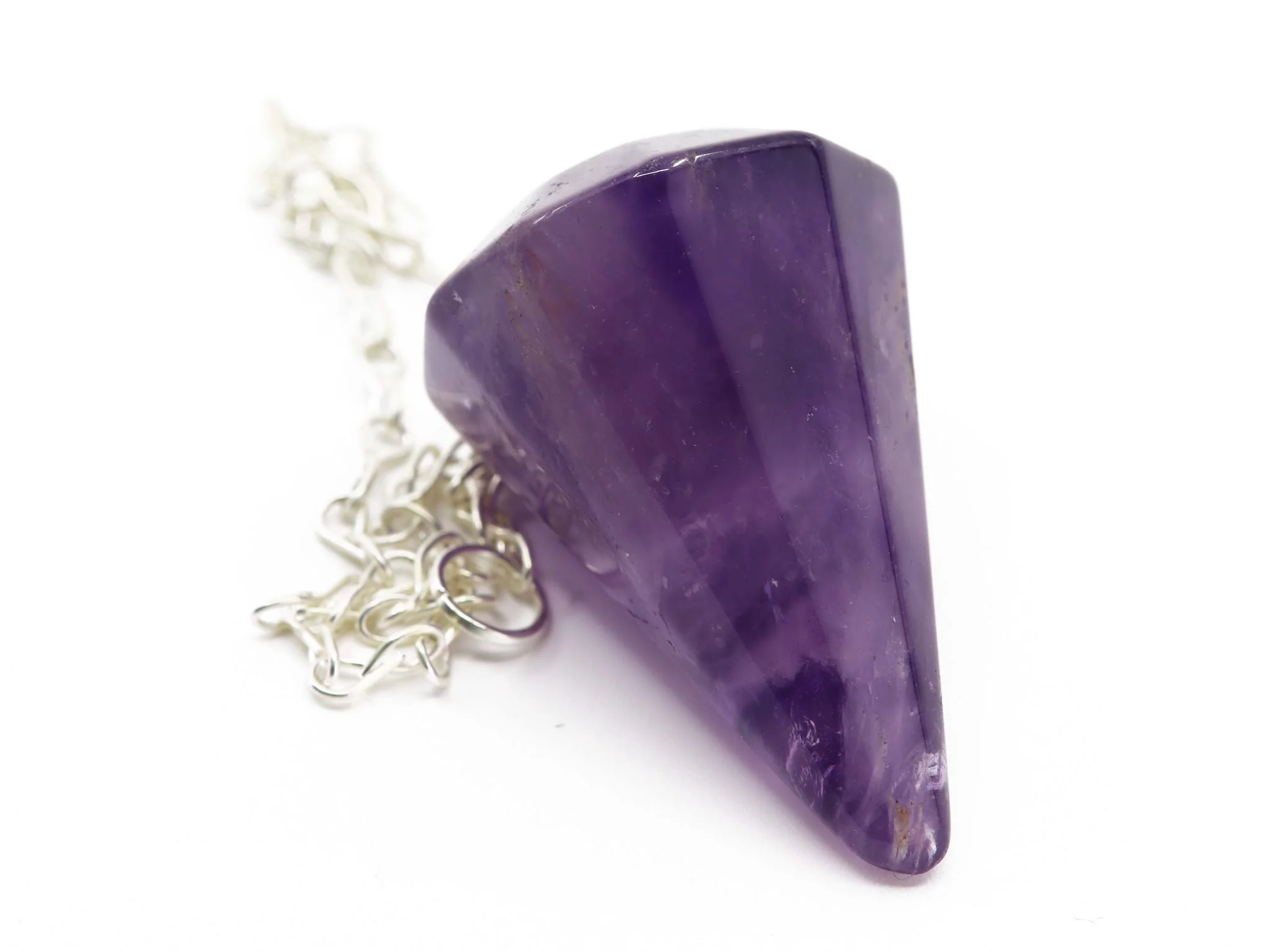 Amethyst pendulum with chain as a close-up of the faceted violet stone surface and suspension