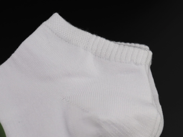 Bamboo sneaker socks in white with a detailed view of the ribbed cuff on a black background