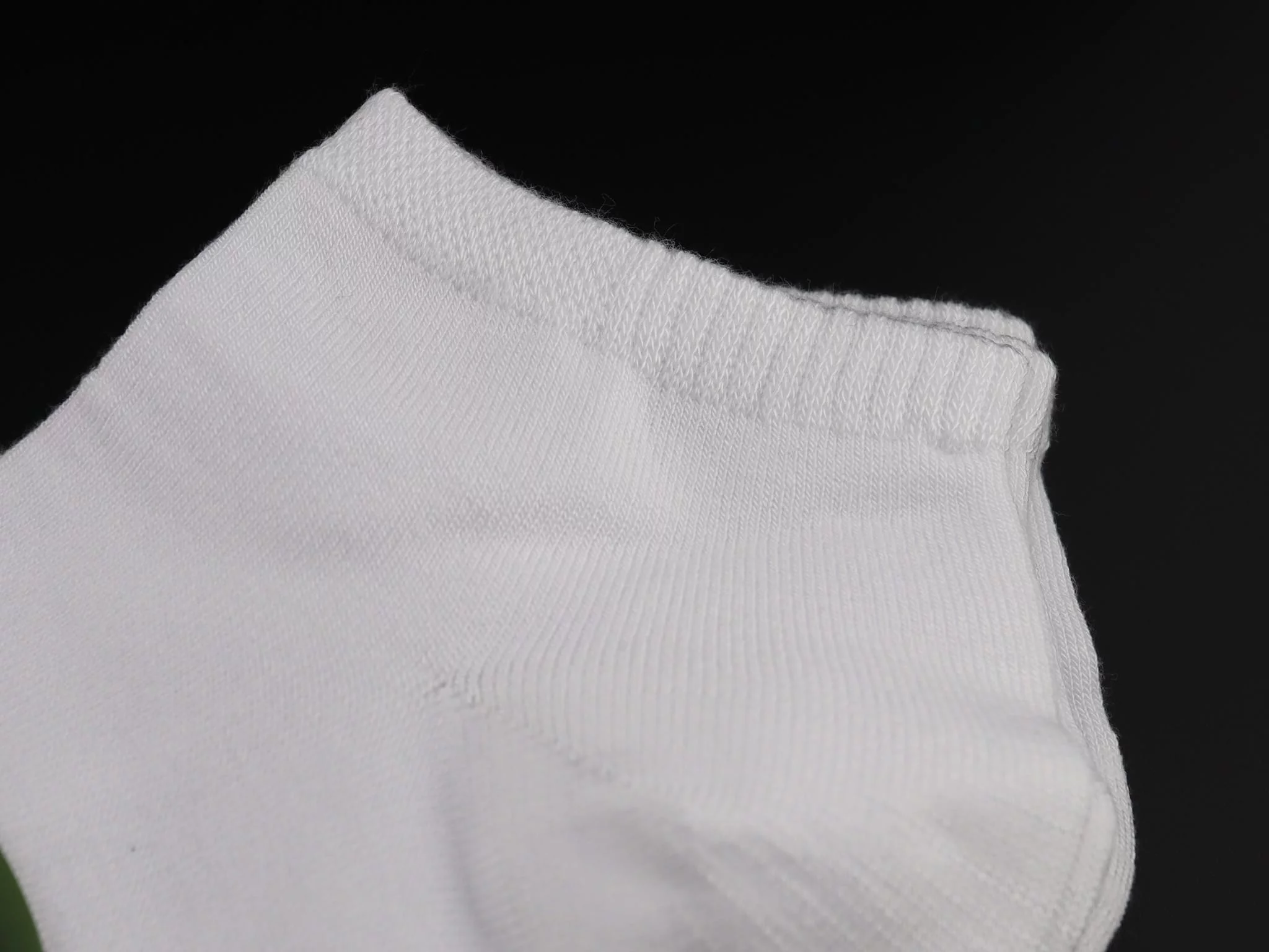 Bamboo sneaker socks in white with a detailed view of the ribbed cuff on a black background