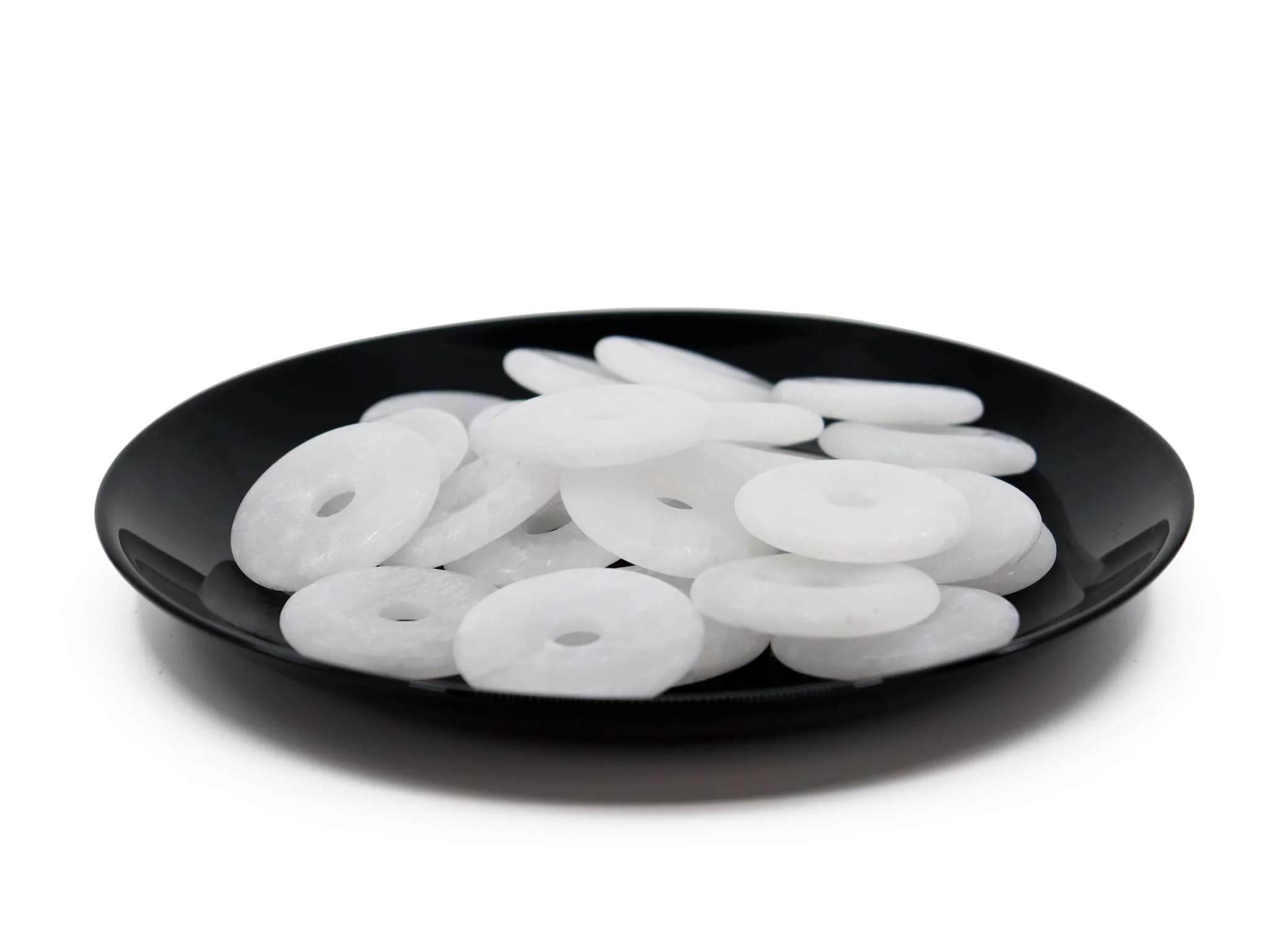 Pendentif donut en baryte blanc neige comme sélection de plusieurs pierres sur une assiette noire