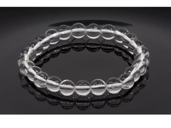 Bracelet en pierres précieuses en cristal de roche avec perles transparentes sur surface noire miroir