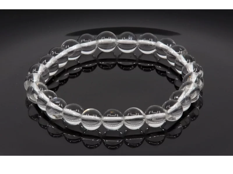 Bergkristall Edelsteinarmband mit transparenten Kugeln auf schwarzer spiegelnder Fläche