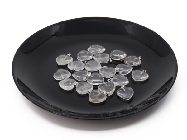 Rock crystal heart gemstone pendant as a selection of several transparent hearts on a black tray