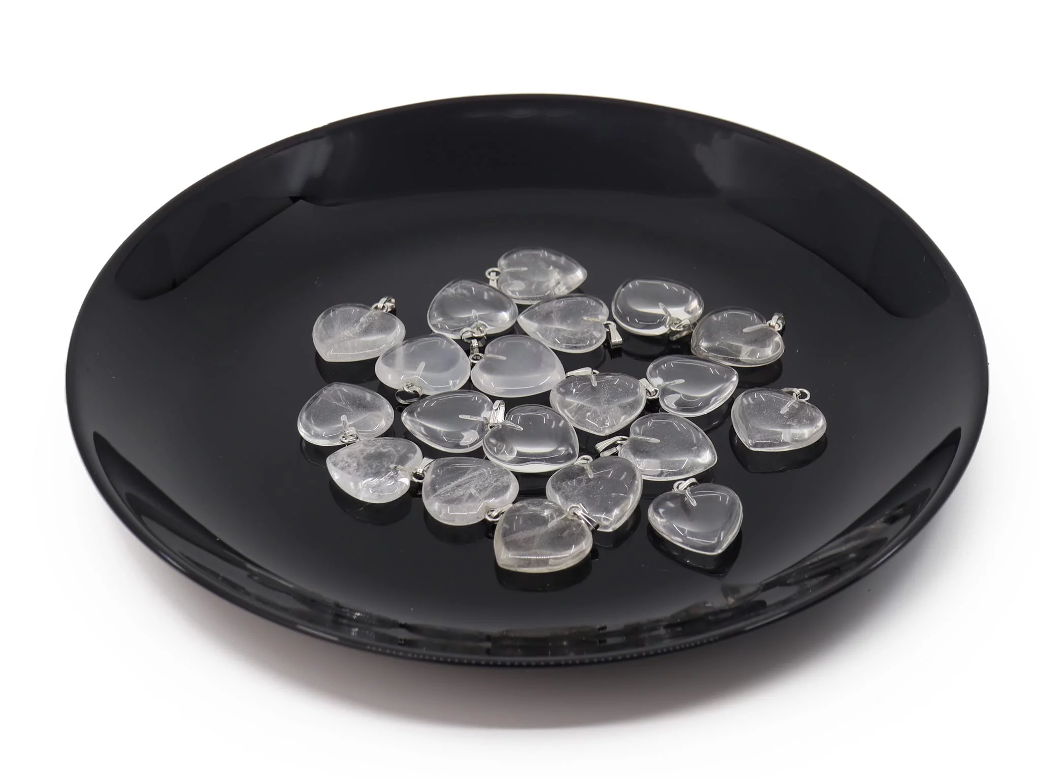 Rock crystal heart gemstone pendant as a selection of several transparent hearts on a black tray