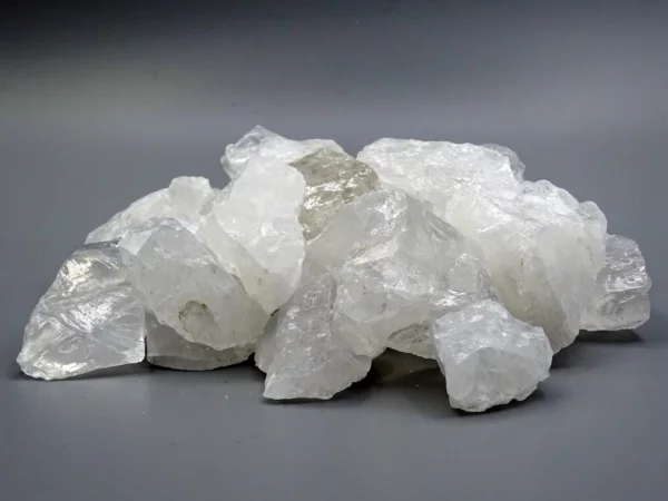 Bergkristall Wassersteine mit unregelmässiger Rohsteinoberfläche auf grauem Untergrund