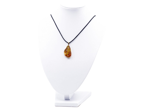 Amber pendant on a black necklace on a white jewelry bust, full view