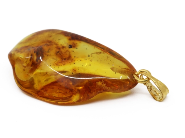 Amber pendant with a glossy yellow-gold surface and brass loop, close-up view