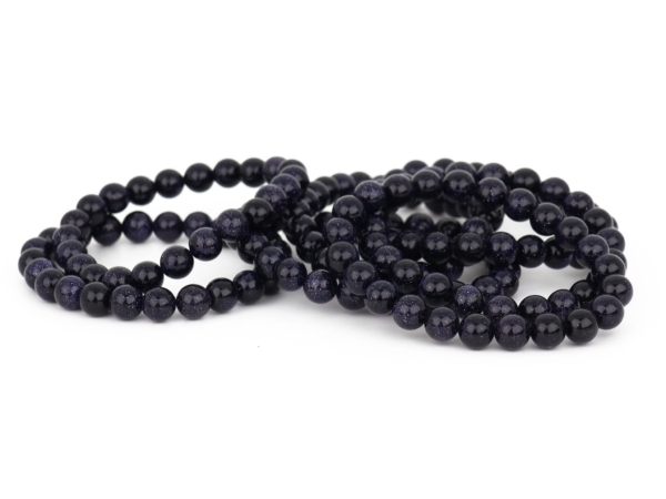 Blue Goldstone bracelet with several dark blue bead bracelets on a white background