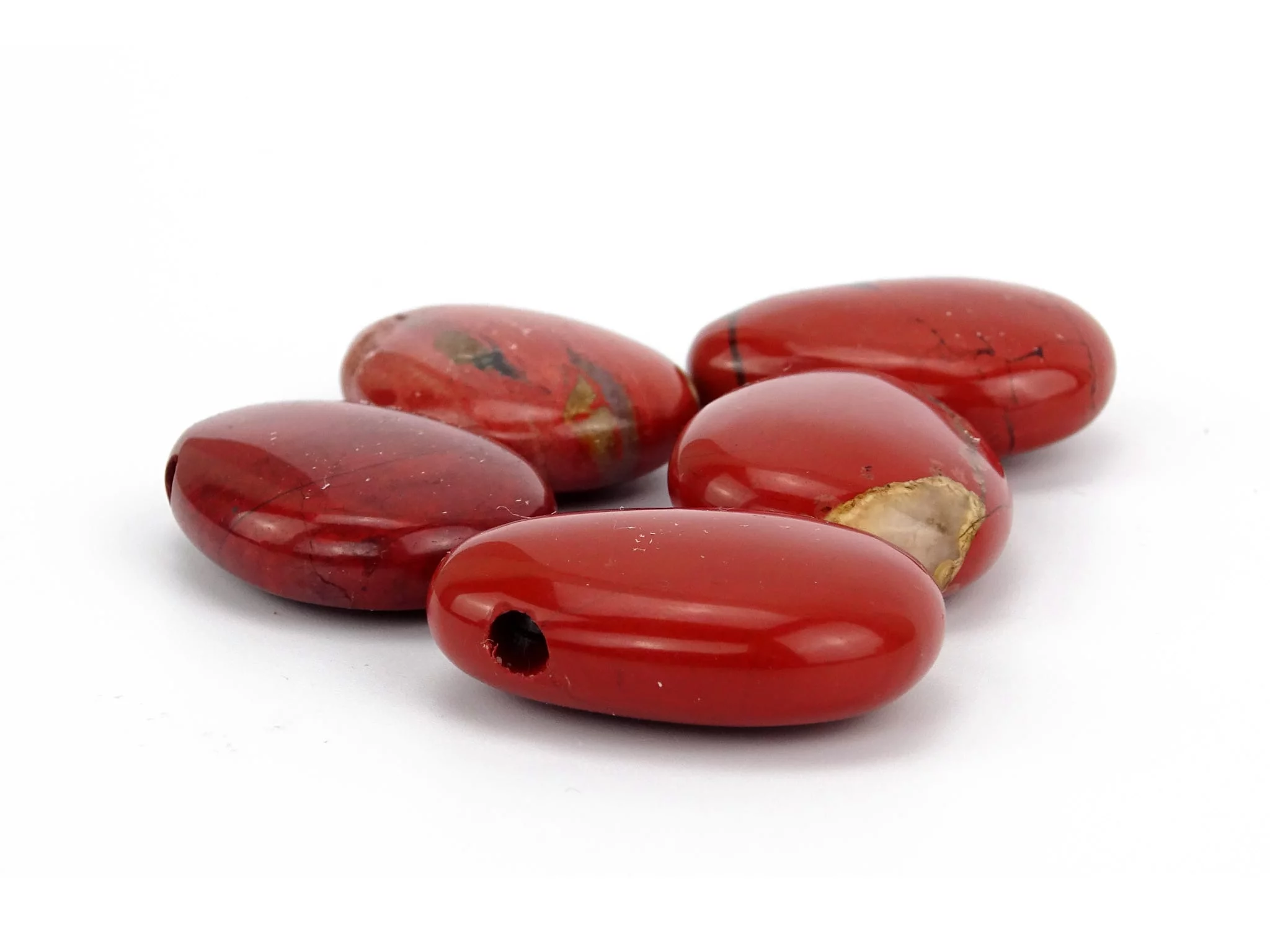 Pendentif en jaspe bréchique comme sélection de pierres percées rouges polies sur fond blanc
