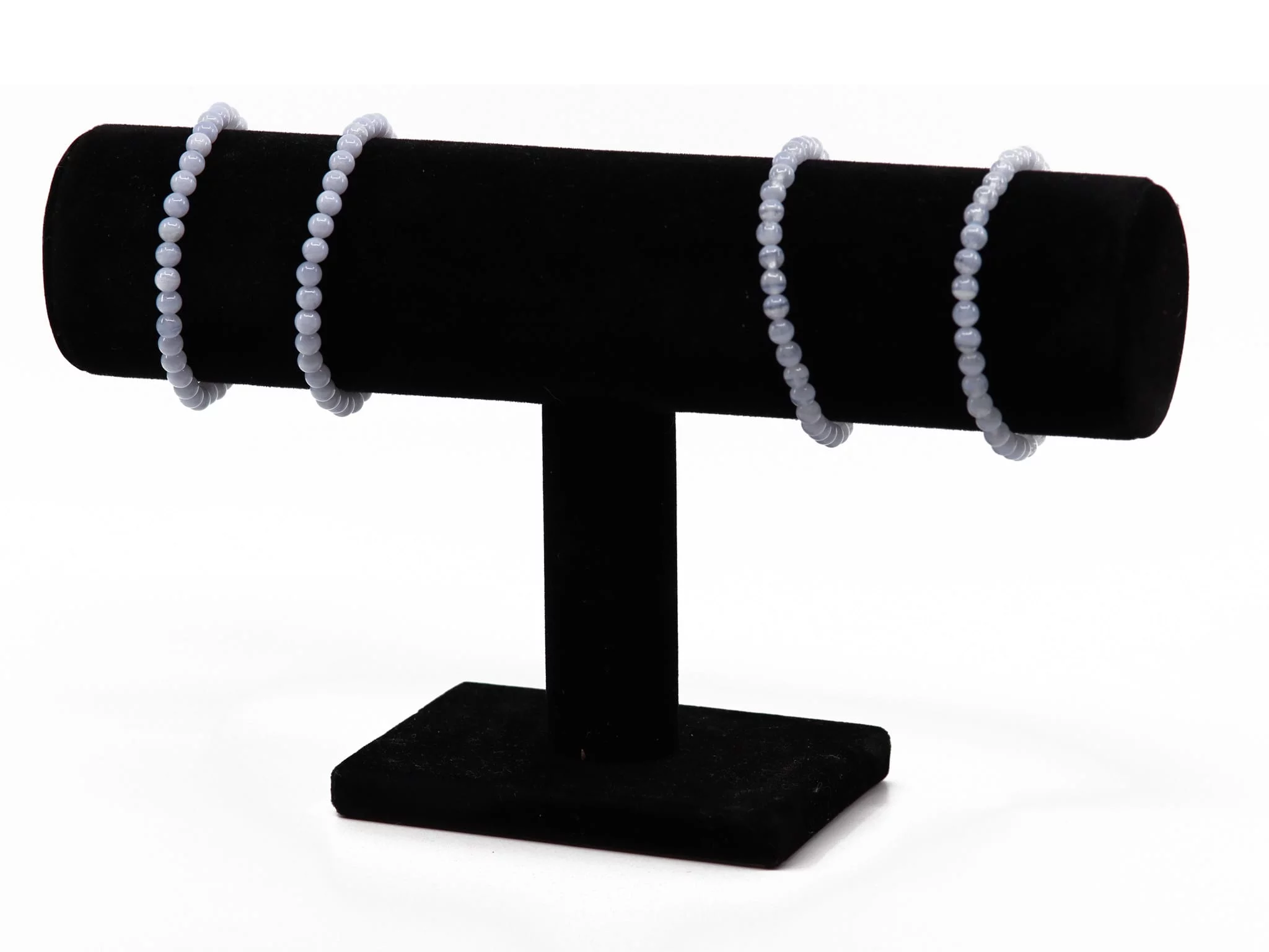 Chalcedony gemstone bracelets on a black jewelry stand with light blue beads