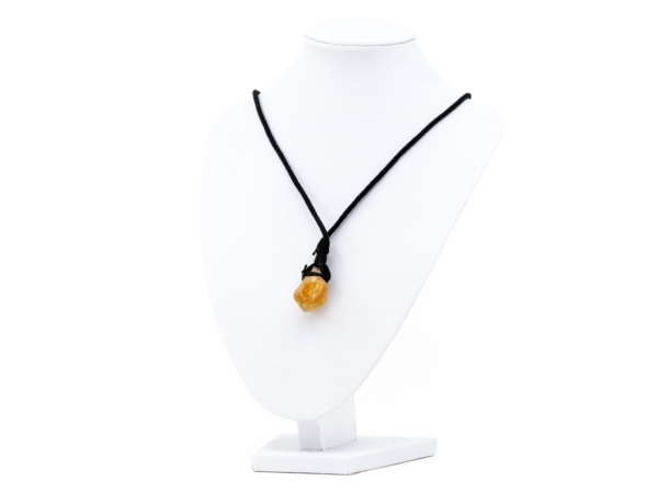 Citrine crystal pendant on a black fabric cord on a white jewellery stand
