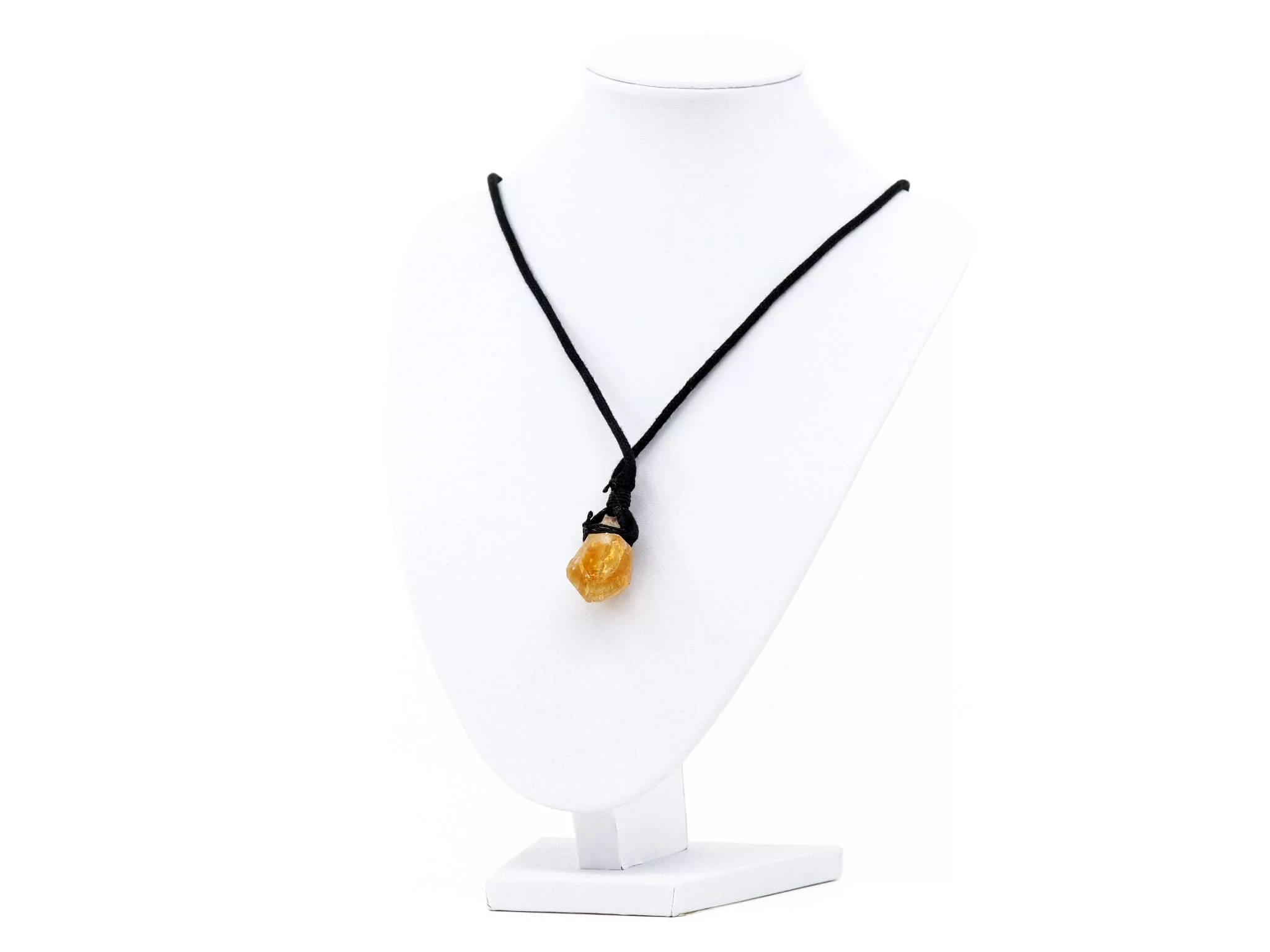 Citrine crystal pendant on a black fabric cord on a white jewellery stand