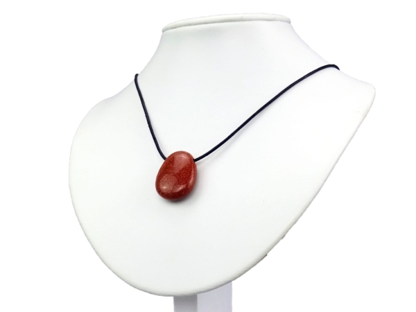Pendentif en rivière d’or porté sur un collier noir sur un buste à bijoux blanc