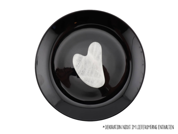 Clear quartz Gua Sha massage stone on black bowl as decorative display