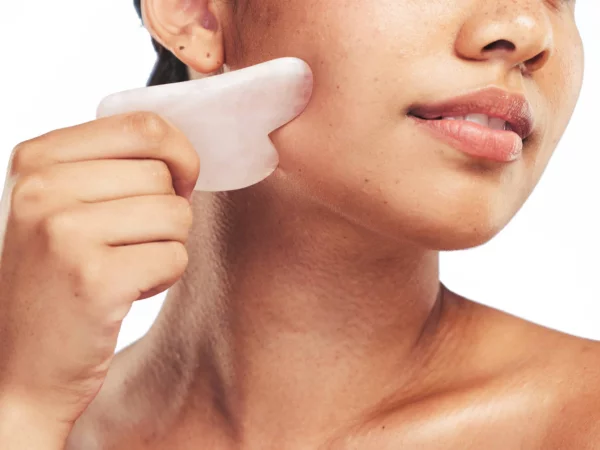 Gua Sha Massagestein Set bei der Anwendung mit einem Stein im Gesicht
