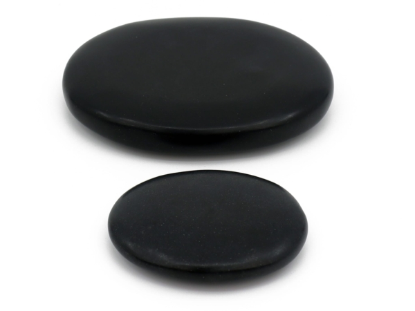 Pierres de massage Hot Stone en basalte en deux versions plates et polies noires sur fond blanc