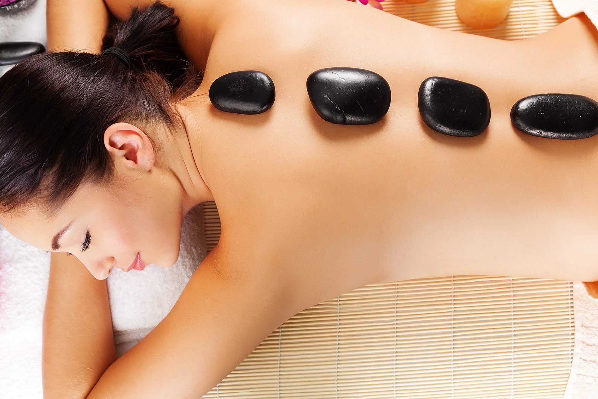 Basalt Hot Stone massage stones placed on a woman's back during a wellness massage