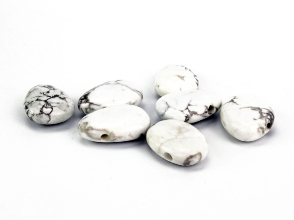 Pietre forate in howlite con fori visibili su sfondo bianco