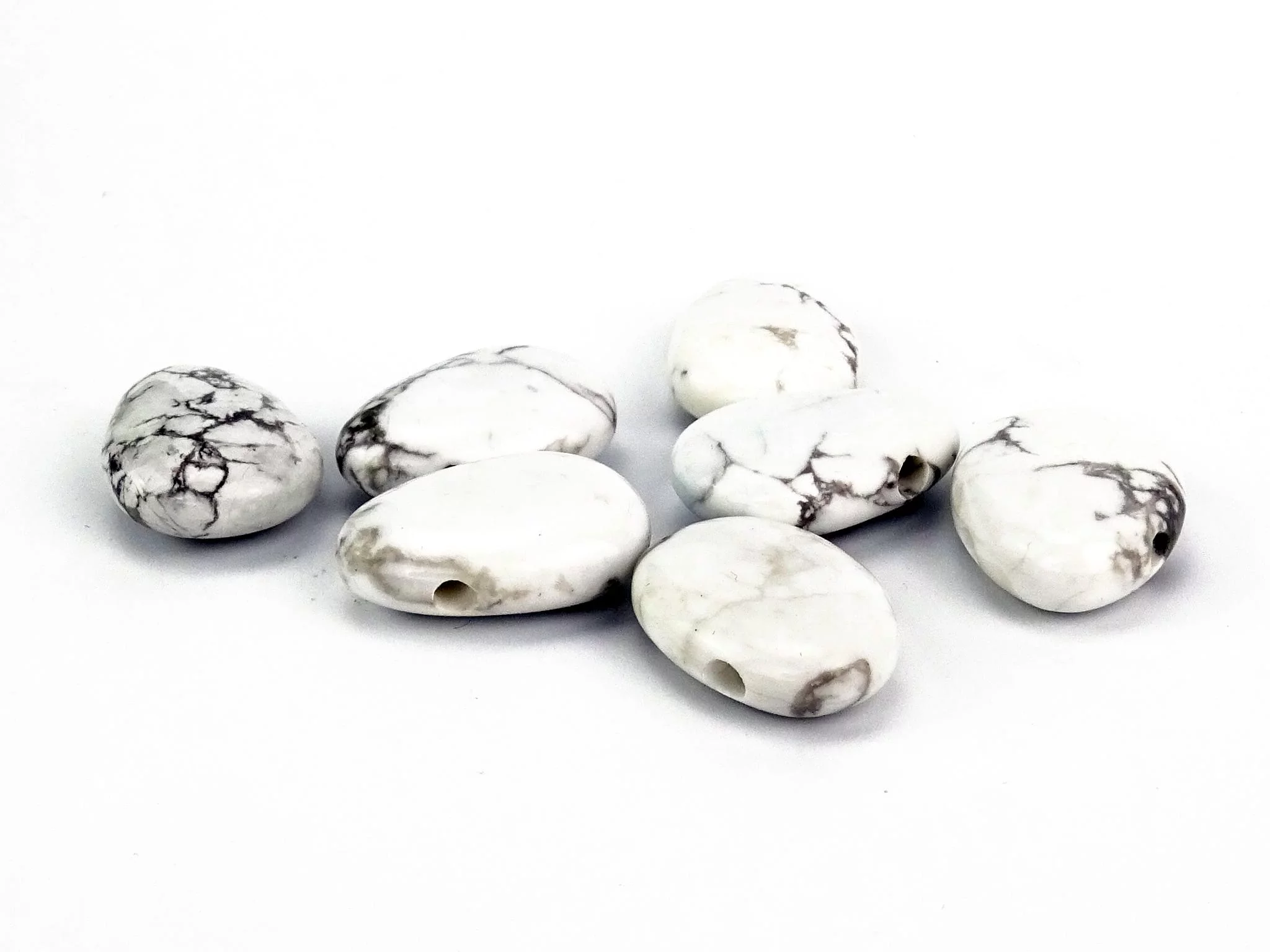 Howlite Lochsteine mit sichtbaren Bohrungen auf weissem Hintergrund