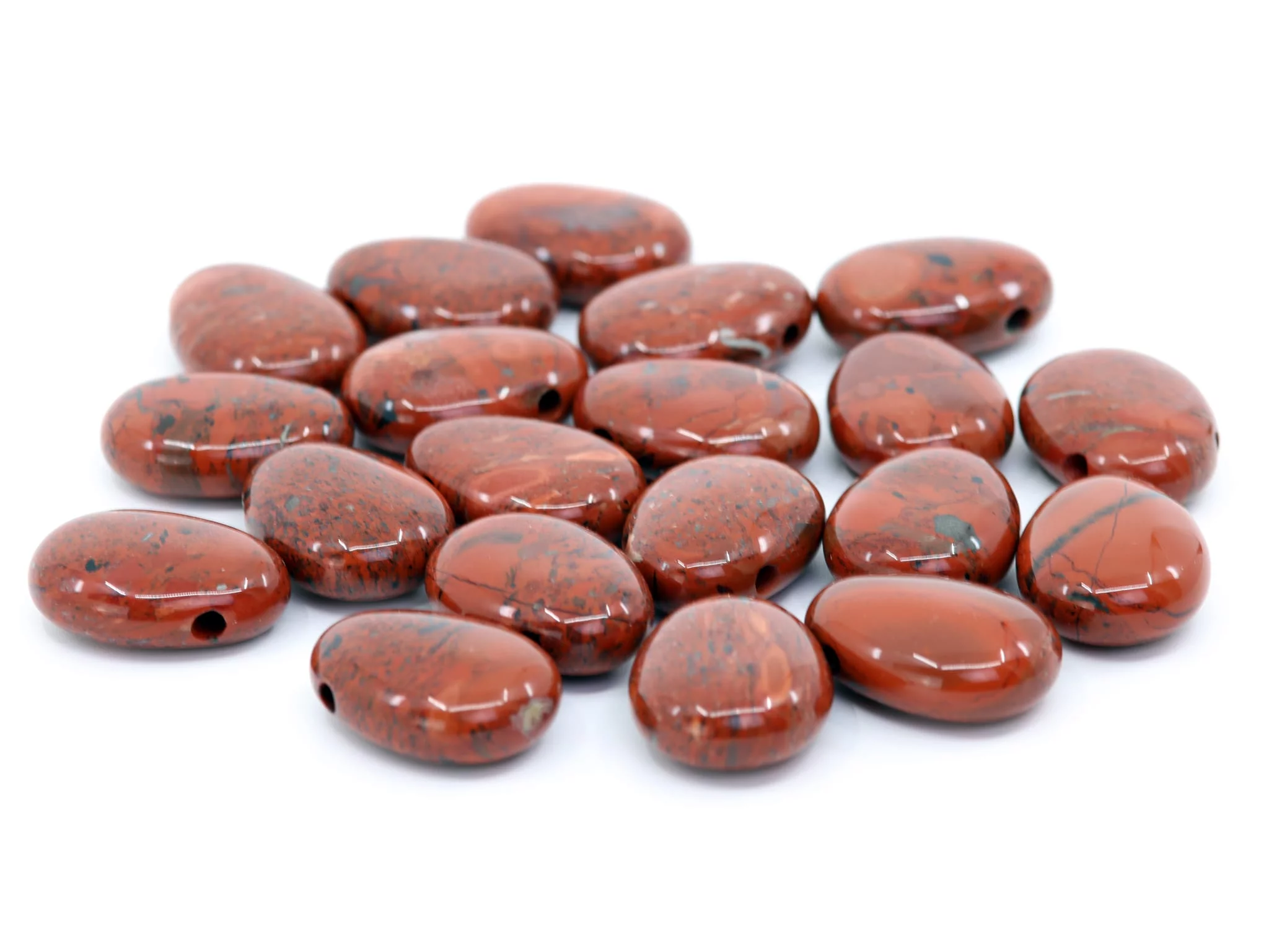 Red jasper drilled stones with dark markings in a group on white background