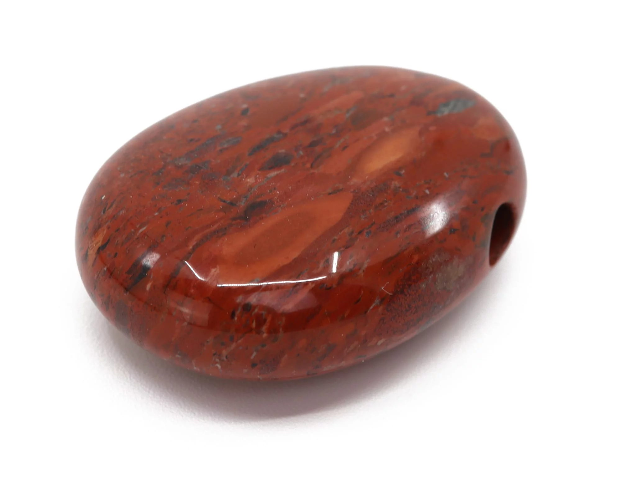 Red jasper drilled stone in close-up with dark natural grain