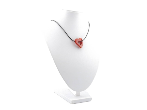 Pendentif cœur en cornaline sur un collier noir sur un présentoir à bijoux blanc