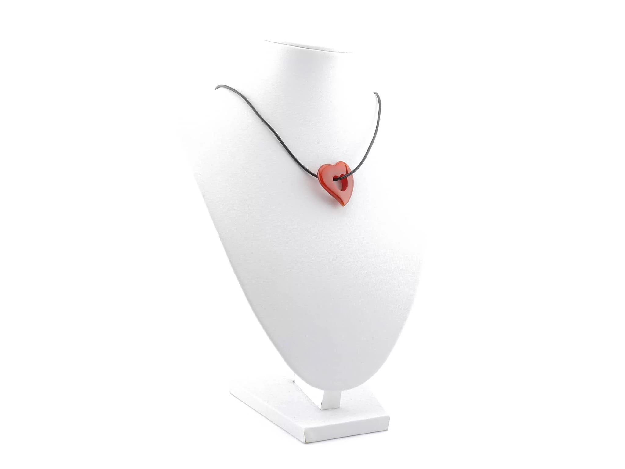 Pendentif cœur en cornaline sur un collier noir sur un présentoir à bijoux blanc