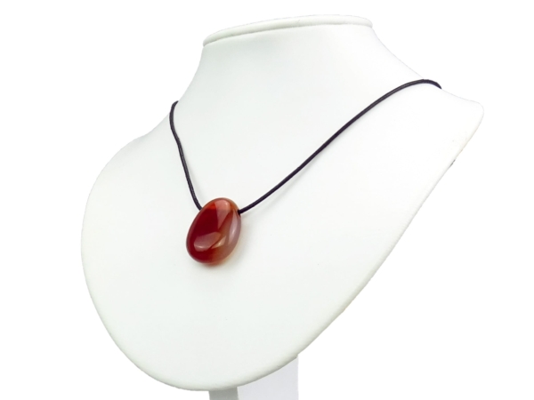 Pendentif en pierre précieuse cornaline porté, sur buste de bijouterie blanc avec collier noir