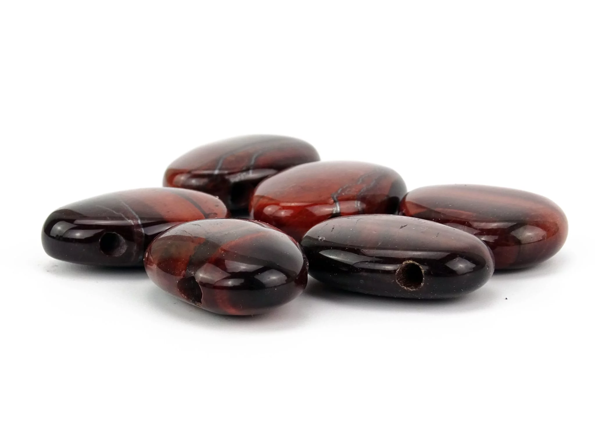 Cat's Eye gemstone pendant as a selection of polished reddish-brown drilled stones with visible holes
