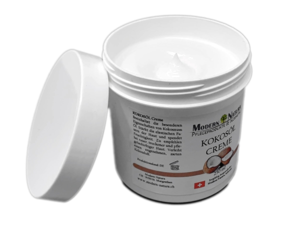 Crème à l'huile de coco dans un pot blanc ouvert avec couvercle retiré et crème visible