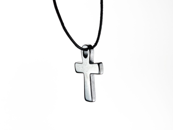Pendentif croix en hématine suspendu à un collier noir sur fond blanc