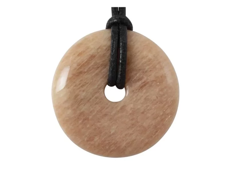 Moonstone donut pendant with polished rose-beige surface and black cord against white background