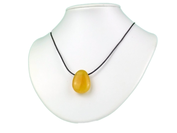 Pendentif en pierre précieuse calcite orange porté sur un collier noir, sur buste blanc