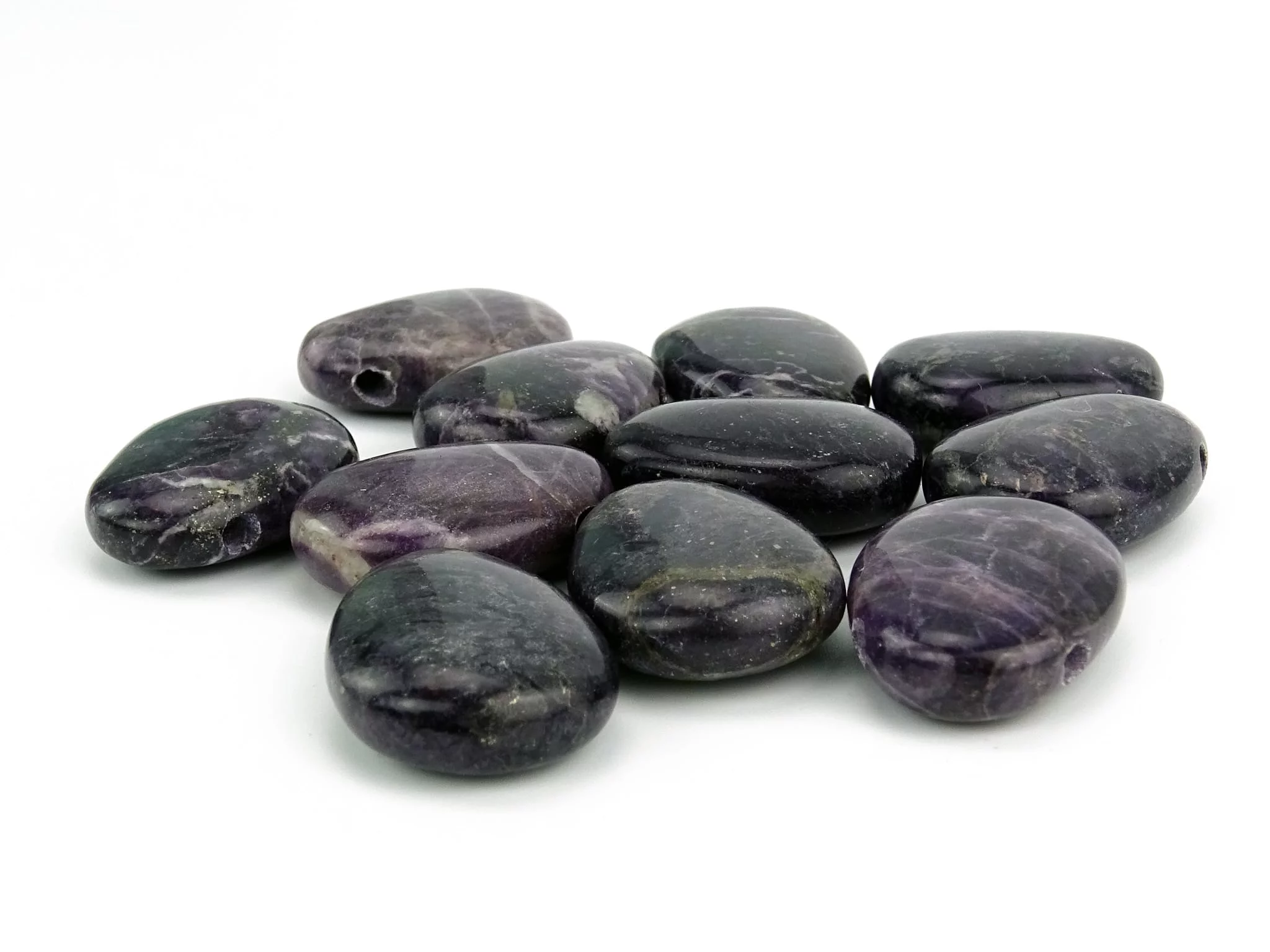 Purple Heart Edelstein Anhänger als Auswahl polierter violetter Lochsteine auf weissem Hintergrund