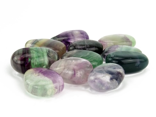 Rainbow fluorite donut stones in various green and violet color patterns on white background