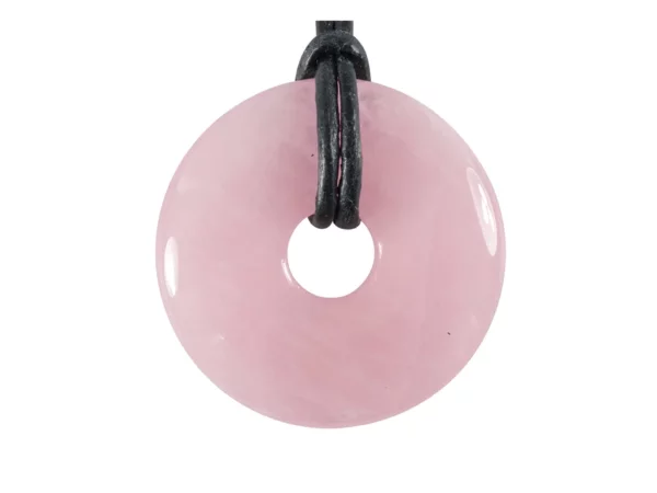 Rose quartz donut pendant in soft pink with black leather cord on a white background