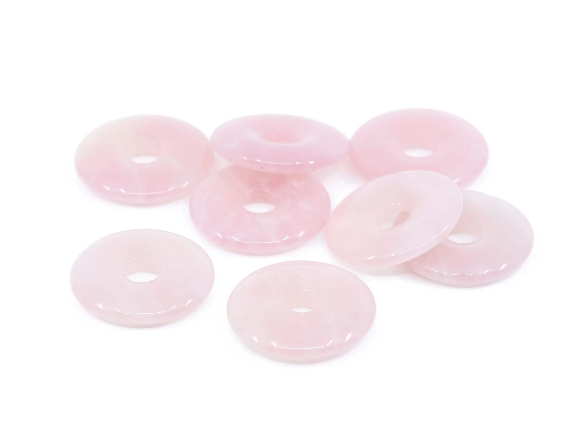 Rose quartz donut pendant showing a selection of several smoothly polished pink holed stones
