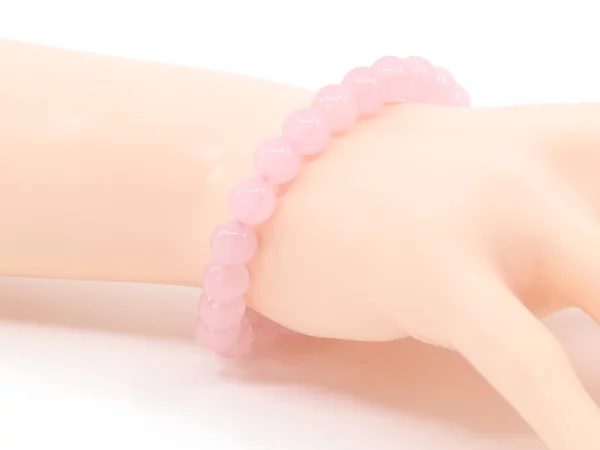 Rosenquarz Edelsteinarmband in Nahansicht am Handgelenk mit glänzenden rosa Kugeln