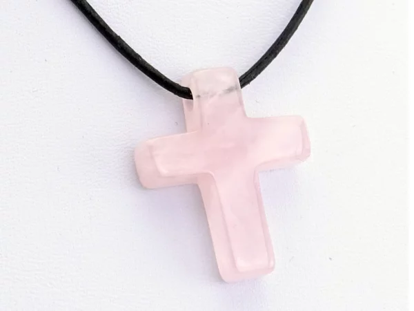 Rosenquarz Kreuz Anhänger in Nahansicht mit schwarzer Lederkette und polierter Oberfläche