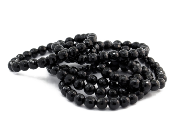 Bracelet tourmaline schorl avec plusieurs bracelets de perles noires facettées sur fond blanc