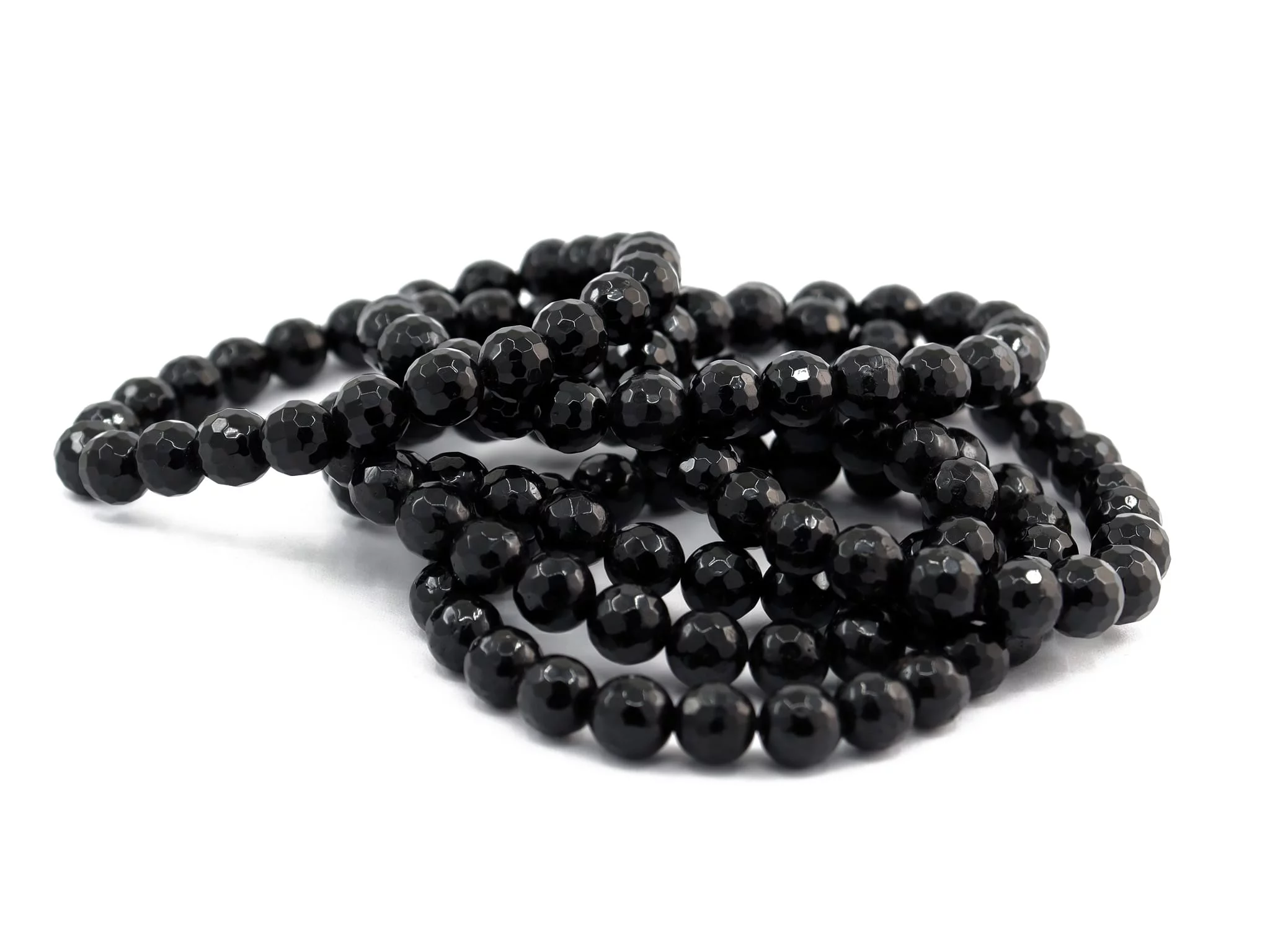 Bracelet tourmaline schorl avec plusieurs bracelets de perles noires facettées sur fond blanc