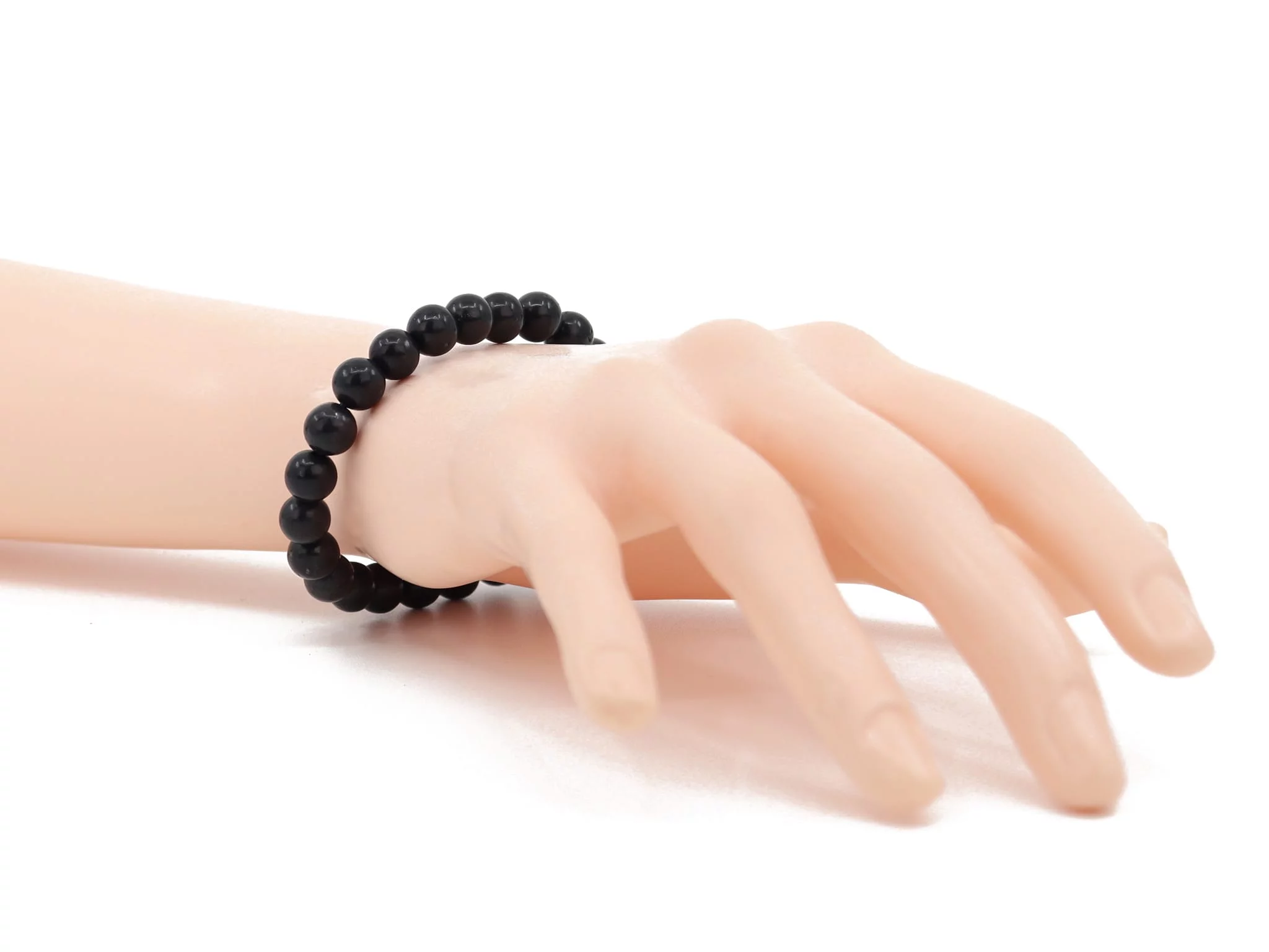 Shungite bracelet with black beads, worn on the wrist on a white background