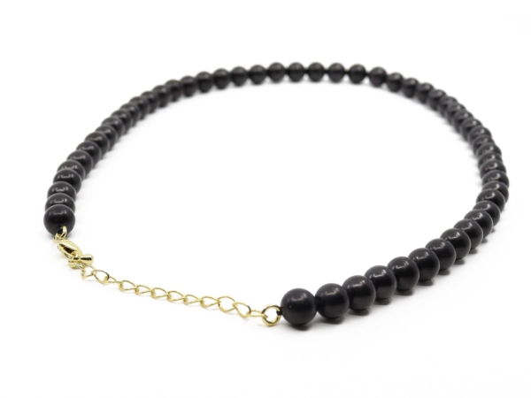 Collier en shungite, gros plan avec boules noires, mousqueton et rallonge à maillons dorée