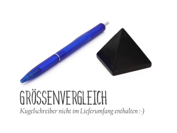 Pyramide en shungite à côté d’un stylo à bille bleu pour comparer la taille sur fond blanc