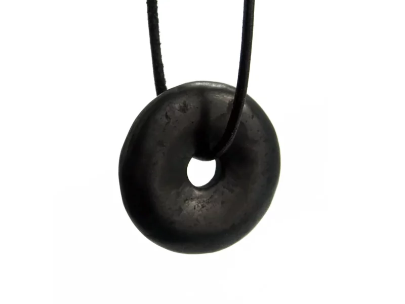 Schungit Donut Anhänger in Schwarz mit schwarzem Halsband in naher Frontansicht auf weissem Hintergrund
