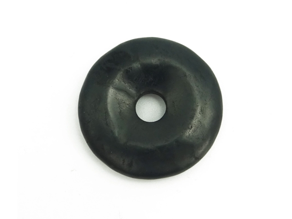 Pendentif donut en shungite noir en vue détaillée de la surface naturelle sur fond blanc